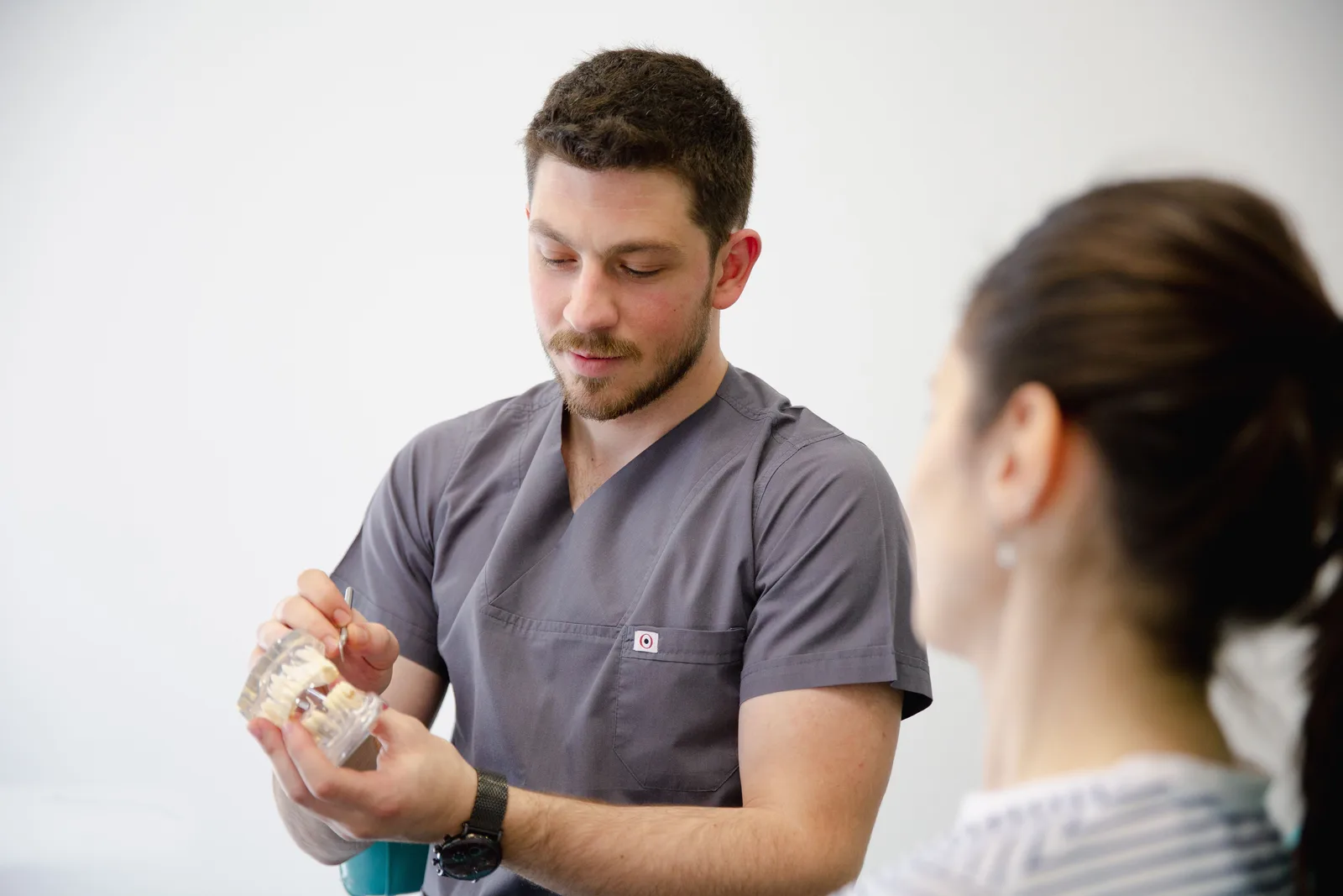 Dentist showing an implant model during a consultation, referred to in the Single Tooth Implant section for Victoria