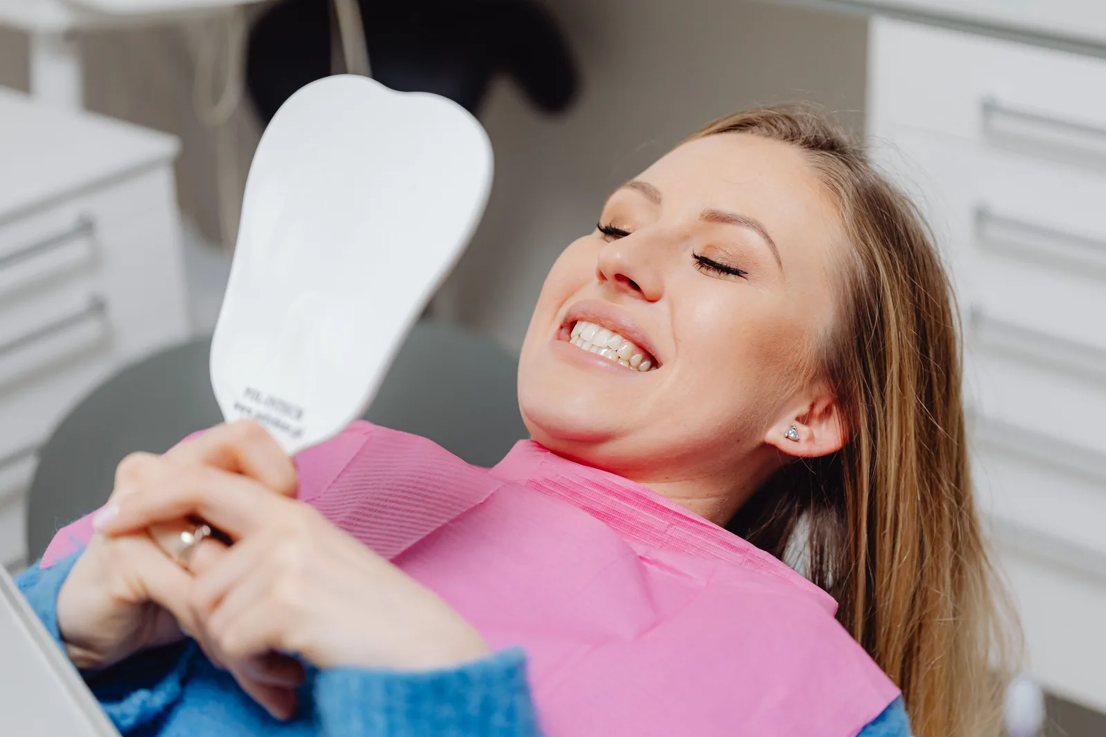 Patient checking her smile in the mirror, shown while covering All-on-6 Implants in Victoria