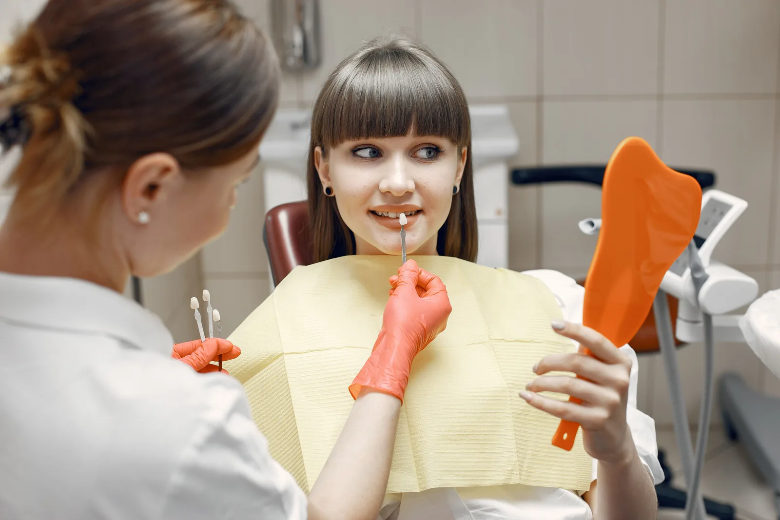 Patient checking crown shade in a hand mirror, shown while covering Single Tooth Implant in Victoria