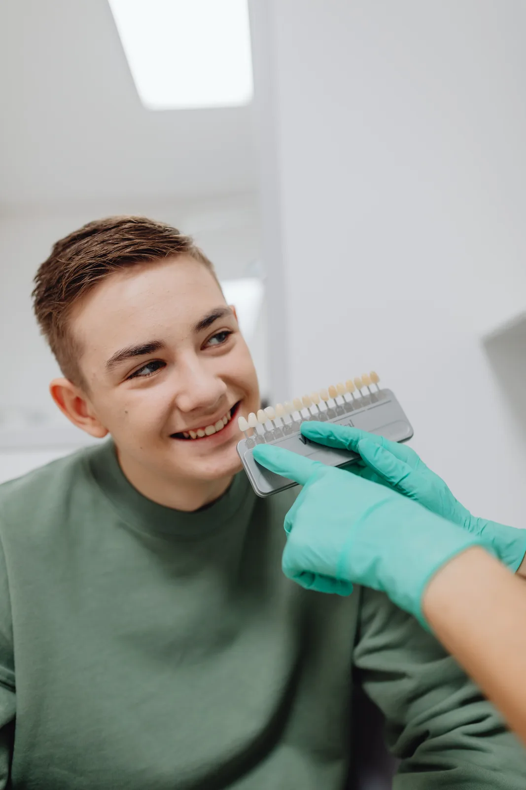 Shade guide held beside the patient smile, shown while covering Dentures Vs Implants in Victoria